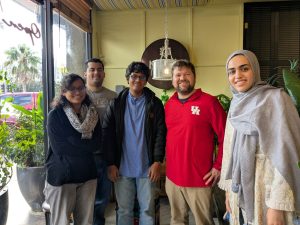 Five group members posing in front of a restaurant.